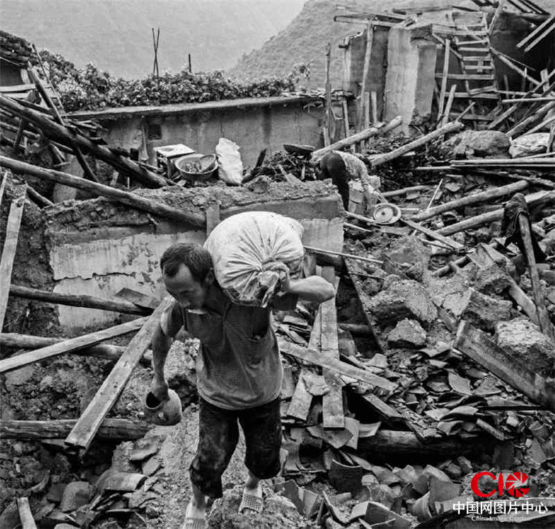 803地震后，灾民在撤离家园前在自家房屋的废墟上寻找一些能带走的生活用品。