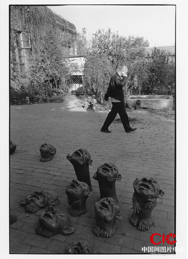 著名藝術家方力鈞從自己的雕塑作品前走過。宋莊鎮小堡村，2005年。