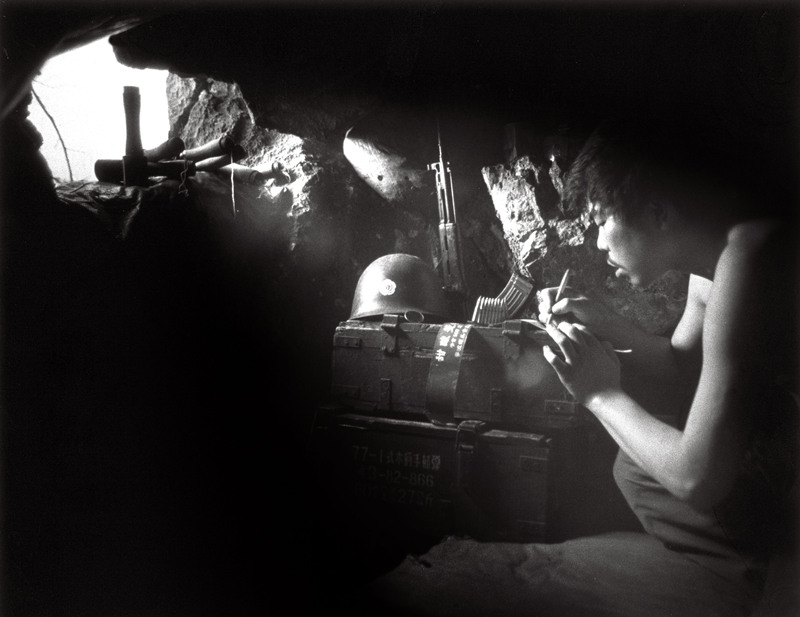 《“亲爱的妈妈……”》1986年6月2日，坚守在三面受敌、距敌阵地仅300米的我军负二阵地上，一位战士在猫耳洞里，利用射入猫耳洞的阳光，在军用罐头盒商标纸背面给妈妈写信，汇报前线战斗、生活情况。柳 军 摄