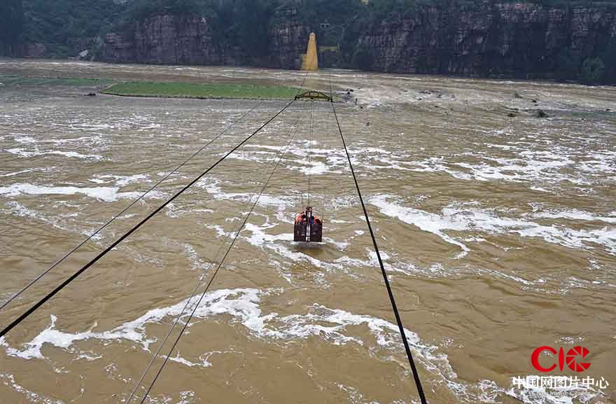 面對洪流，水文人不懼艱險，利用空中吊籃在水上監測河道流量和水位。