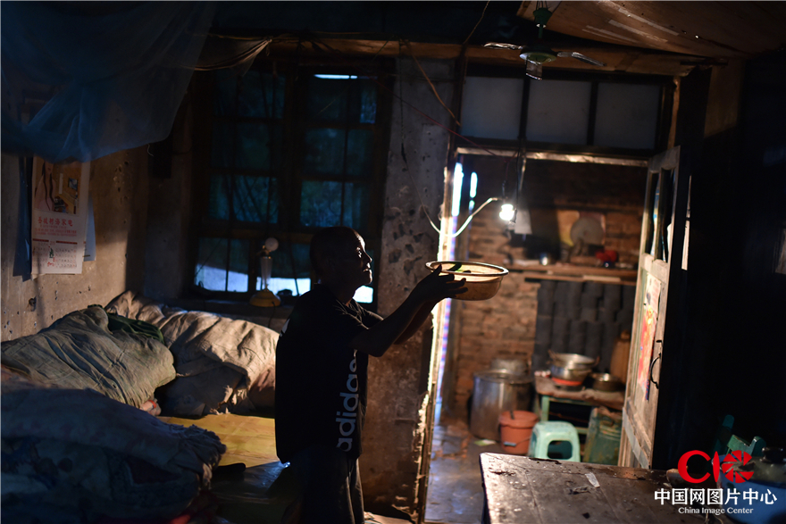 8月1日，磁县岳城镇岳城村，68岁的李明希老人撤掉接雨的水盆。他的房子年久失修，漏水严重。大雨中，村干部把他安全转移后为他修了房子。