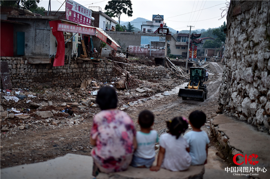 8月2日，磁县中岔口村，老人和孩子静静地观看灾后重建“现场直播”。
