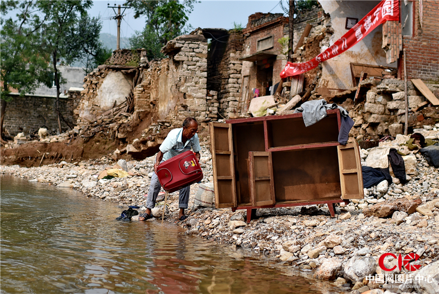 8月4日，磁县五里河村，一名受灾群众在被冲洗晾晒家具和生活用品。