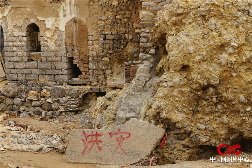 石头上写着的“洪灾”字样和背景被冲毁的房子，似乎在警示着世人勿忘危险  陈勇 摄