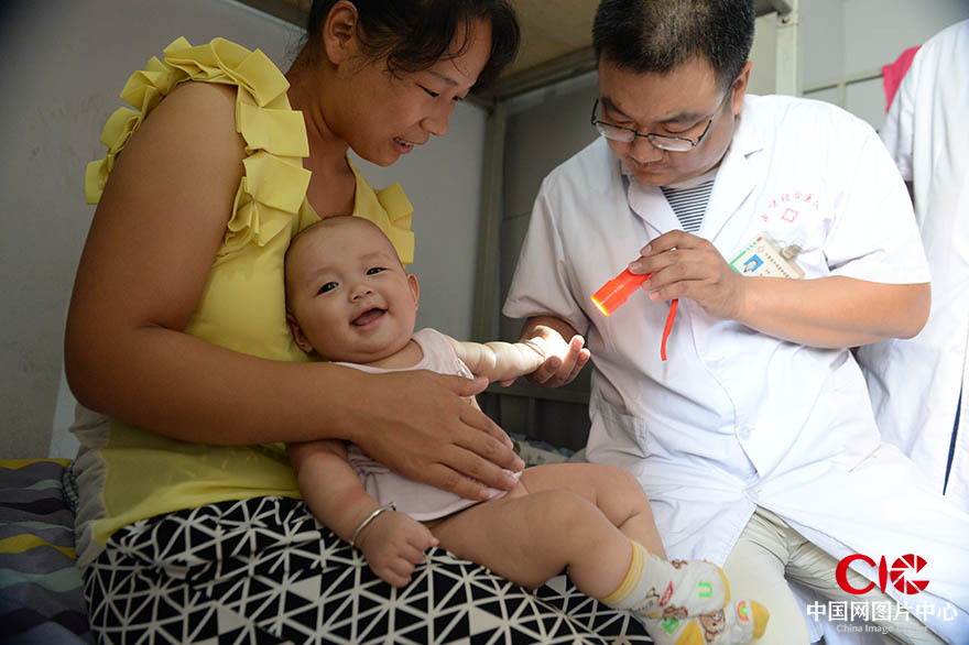 7月23日，在寧晉縣第六中學安置點，醫護人員正在為出生5個月的小妙穎檢查身體 邢臺日報黃濤 攝