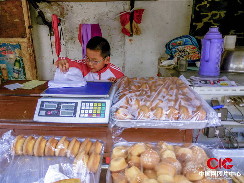 2016.5  石市城中村南王。男孩在媽媽的蛋糕店裏寫作業，順便幫媽媽代賣蛋糕。