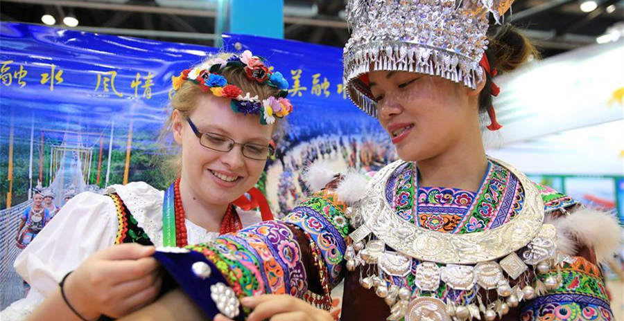 　6月17日，來自廣西柳州融水苗族自治縣的張鳳媚（右）向波蘭觀眾安娜介紹苗族服飾。